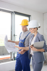 Construction worker and architect looking at plan on site