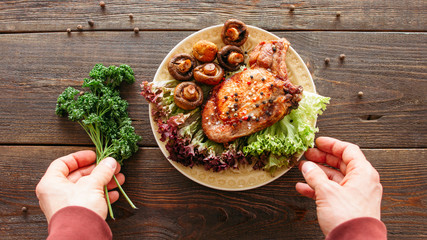 Food stylist decorating meal. Meat dish with lettuce and mushrooms. Chef adding herbs to grilled...
