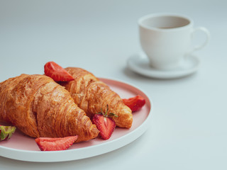 Summer morning with croissants, fresh breakfast with strawberry, and coffee. Closeup