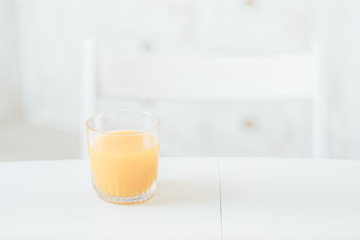 Healthy diet. Balanced nutrition breakfast. Glass of orange juice on white table in kitchen. Blur background. Copy space.