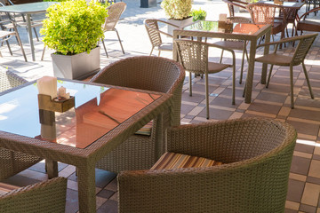 outdoor summer cafe with glass table and flower beds