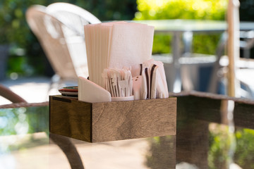 box with paper napkins on a glass table, close-up. part of the table setting outdoor summer cafe