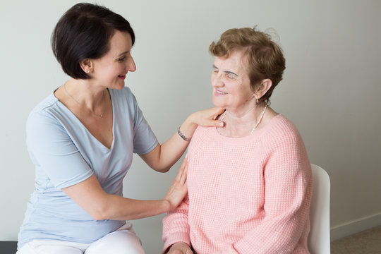 Young Female Holding Hand On Shoulder Of Elderly Woman 