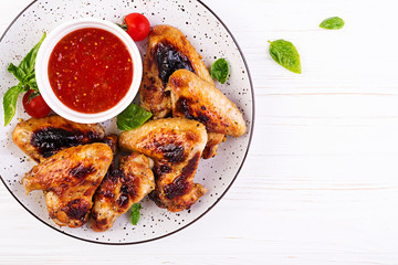 Baked chicken wings in the Asian style and tomatoes sauce on plate. Top view