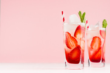 Fresh cold alcohol drinks with strawberry liquor, slices fruit, ice, straw, mint on elegant pink...