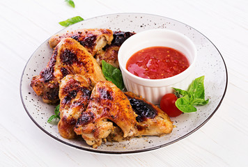 Baked chicken wings in the Asian style and tomatoes sauce on plate.