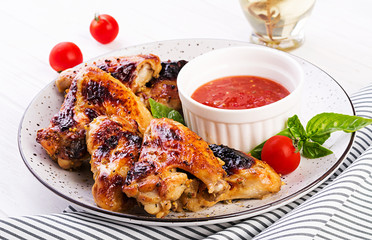 Baked chicken wings in the Asian style and tomatoes sauce on plate.