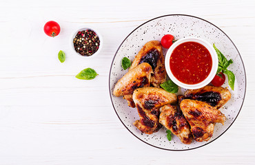 Baked chicken wings in the Asian style and tomatoes sauce on plate. Top view