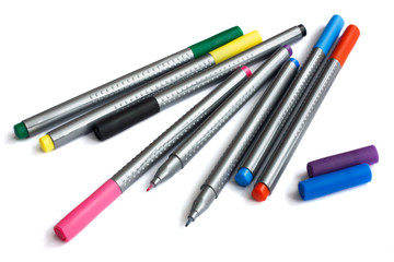 Multi-colored markers leat on white paper, top view