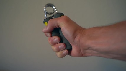Slow motion of a man working on his grip and forearm strength with a handgrip strengthener (120fps to 30 fps) - Powered by Adobe