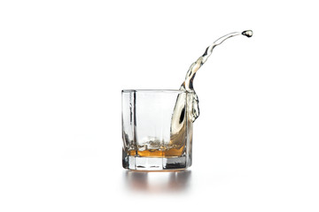Whiskey splash in glass with ice on light background..