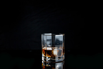 Glass of whiskey with ice isolated on black background..