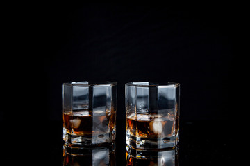 Two glasses of whiskey with ice isolated on black background..