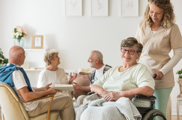 Senior woman on wheelchair with professional caregiver supporting her