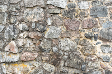 Stone wall texture. Colorful granite stone background. Old Vintage Stone Wall of Historical Medieval Castle in North Europe. 