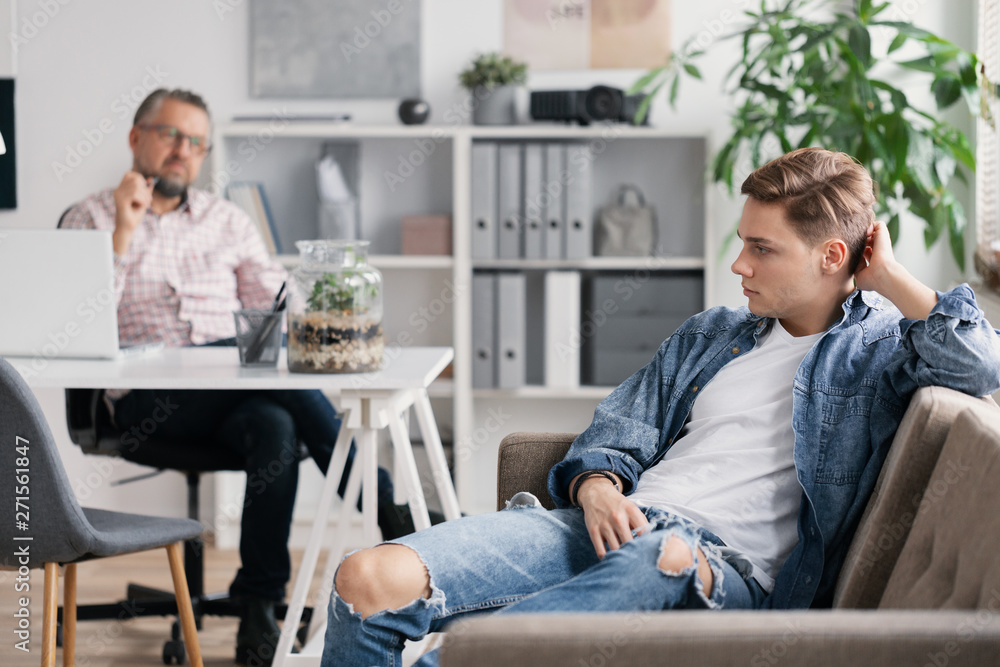 Wall mural professional therapist and teenage boy ignoring him during appointed meeting