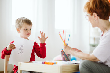 Boy in red sweater learning to count during extra-curricular activities