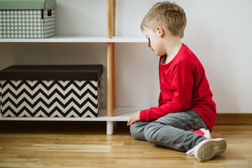 Naklejka premium Kid with depression sits in the corner of the room, and lose interest in activities and schoolwork