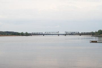 Beautiful water view on a cloudy day in a small port city with boats and bridge.