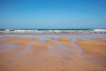 Sandy beach at low tide. Ocean on a sunny day