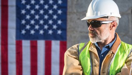 American builder looking sideways with stars and stripes flag in background
