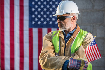 American builder looking sideways with stars and stripes flag in background