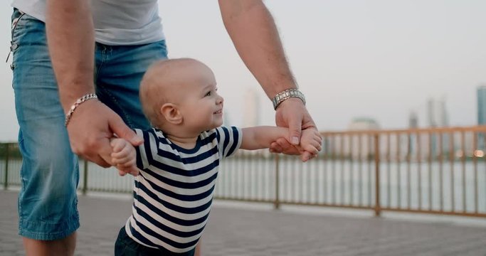 Smiling cute baby takes first steps in summer on the waterfront