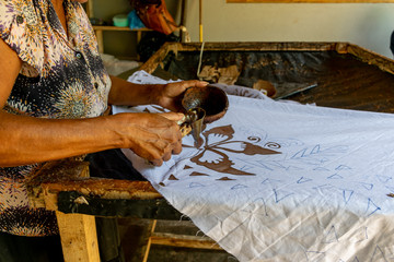 A local woman hand painting fabric in a local Batik fabric factory. The manufacture and export of textile products is one of the biggest industries in Sri Lanka.
