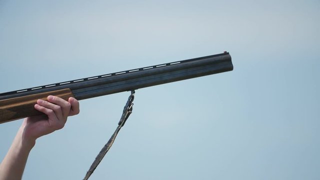 Double-barrel shotgun shooting and cartridge case flying out in summer in slo-mo 