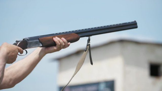Pro man aiming with his double-barrel rifle and shooting at pigeons in slo-mo 