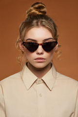 Cropped shot of blonde lady, wearing shirt. The girl with bun and wavy hair locks in cat eye-shaped...