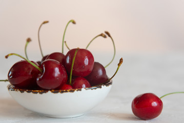 Cherry on a white plate on a light background. Close up.