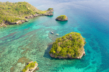 Small rocky island in the blue lagoon, view from above. Bay with turquoise water and coral bottom.