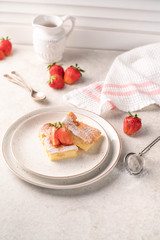 a dessert, vanilla cake with sugar powder and strawberry, on a plate, on a light marble backdrop, 