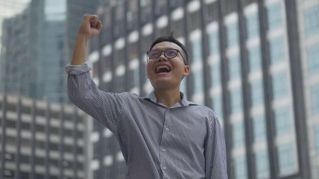 Portrait handsome asian businessman after a working have success and achievement standing looking around urban city. Slow motion low angle shoot.