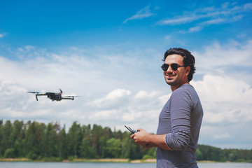 Young Man watching and navigating a flying drone in blue clear Sky