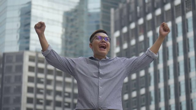 Portrait handsome asian businessman after a working have success and achievement standing looking around urban city. Slow motion low angle shoot.