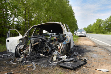 Fully burned car on roadside after collision with heavy truck