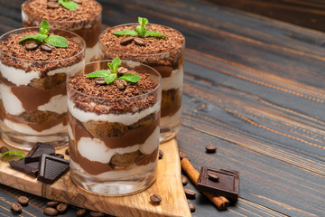 Classic tiramisu dessert in a glass on wooden background