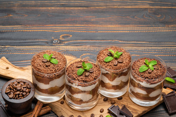Classic tiramisu dessert in a glass on wooden background