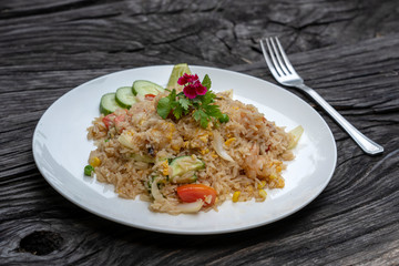 Fried rice with shrimps and vegetables in a white dish on an old wooden table, close up . Thai food , Thai cuisine