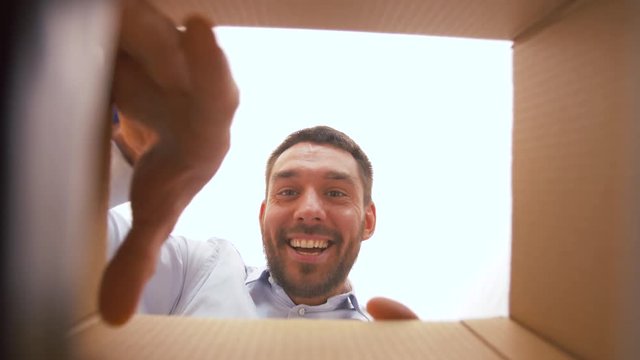 presents, delivery and surprise concept - happy man opening parcel box