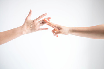 Two person playing rock paper scissors; one hand showing paper symbol and another hand showing scissors symbol; concept of business competition.
