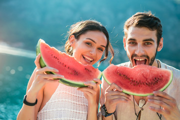 Cheerful couple holding slices of watermelon