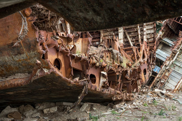 Huge rusty pieces of decommissioned marine ship that was cut and left on the shore.
