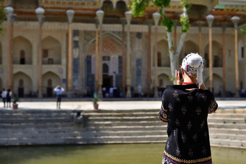 Fototapeta na wymiar Bukhara, Uzbekistan, Tourist on the main square admiring ancient monuments of Bukhara of architectural pearl on the Silk Route 