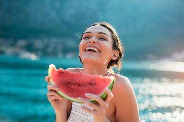 Attractive young woman on the beach eating watermelon