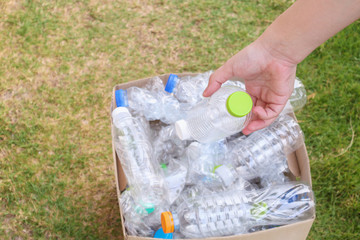 Hand hold and put plastic bottles in to brown recycle garbage box