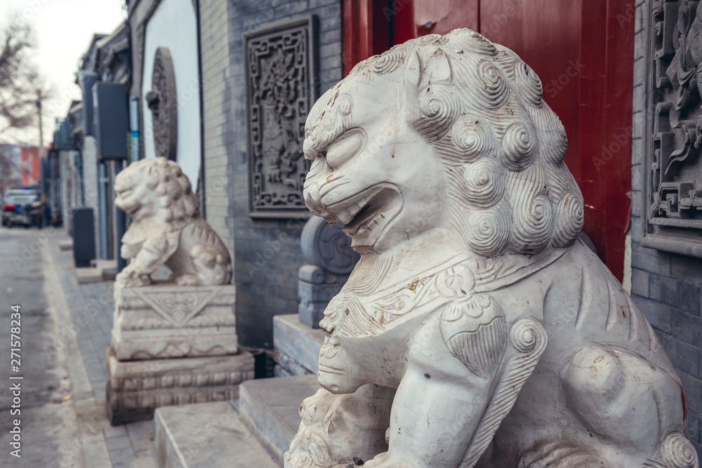 Wall mural Lion sculptures in front of a house entrance in alley called hutong - traditional residential area in Beijing, capital city of China