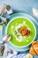 Healthy homemade asparagus vegetable cream soup in a bowl on light blue slate, stone or concrete background. Copy space.